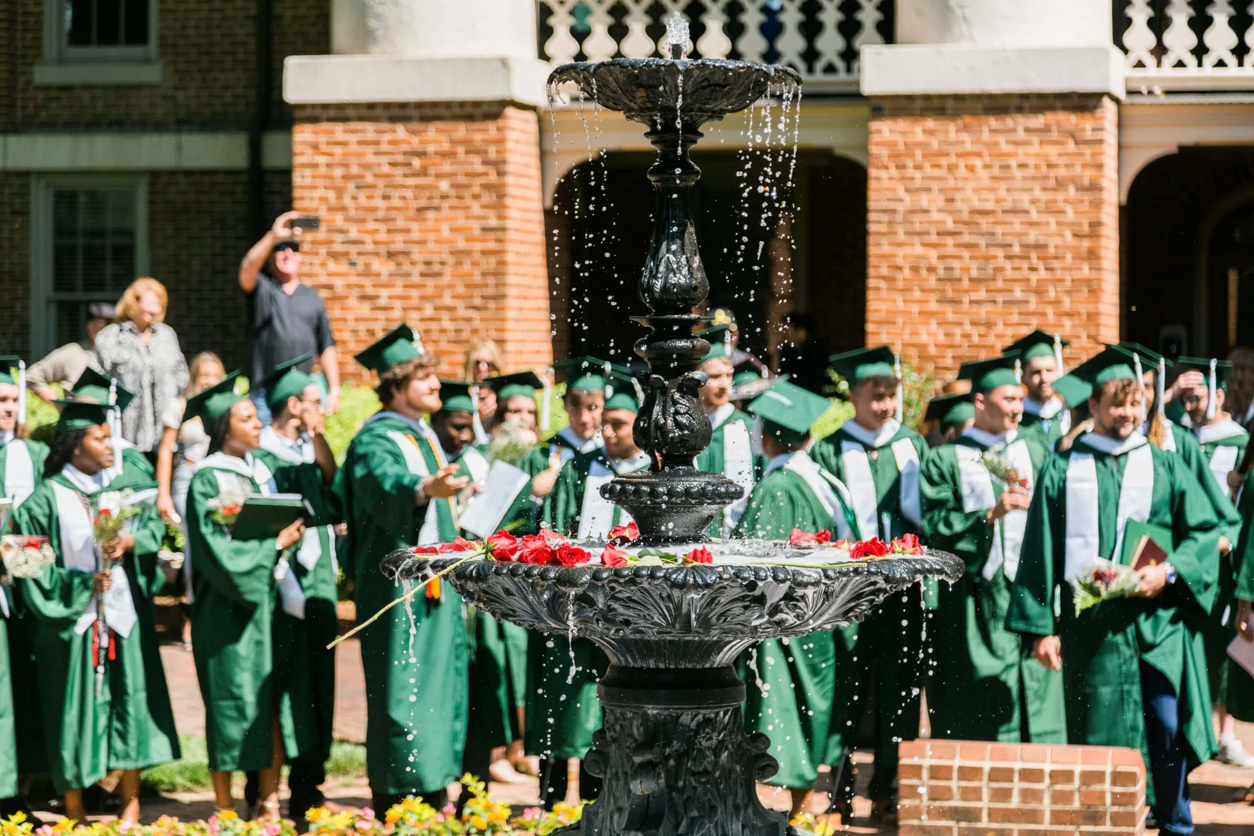 Graduates enjoy a moment by the fountain after Commencement