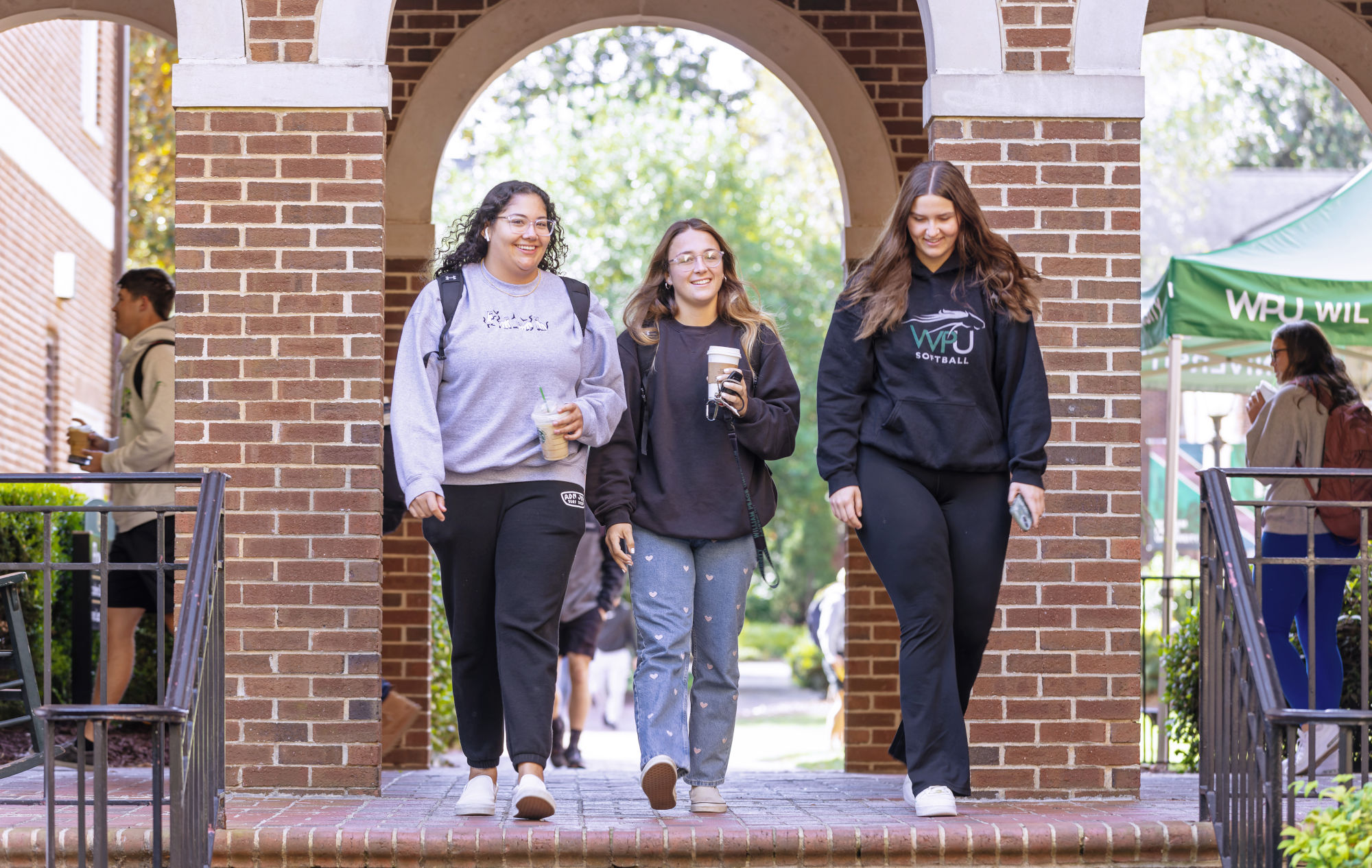 Three WPU students walk through a brick archway on campus.